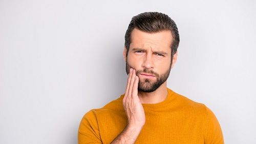 bărbat cu dureri dentare din cauza unei măsele și probabil are nevoie de extracție sau de tratament de canal