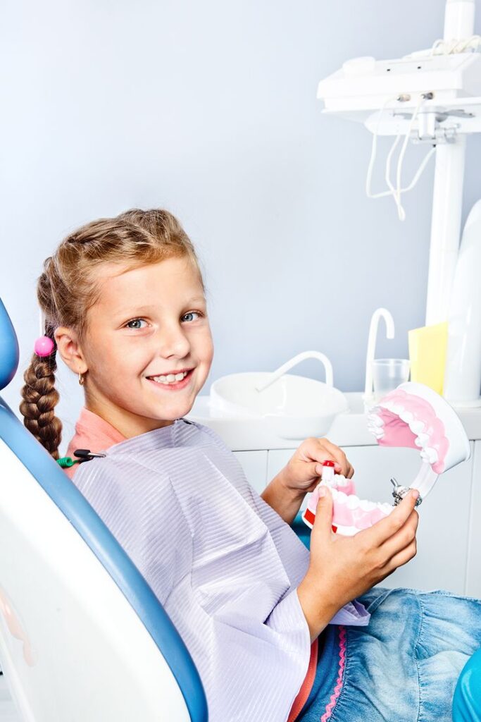 fetiță blondă, copil la dentis, zâmbind cu un zâmbet alb și sănătos. Stomatologie copii, pedodonția